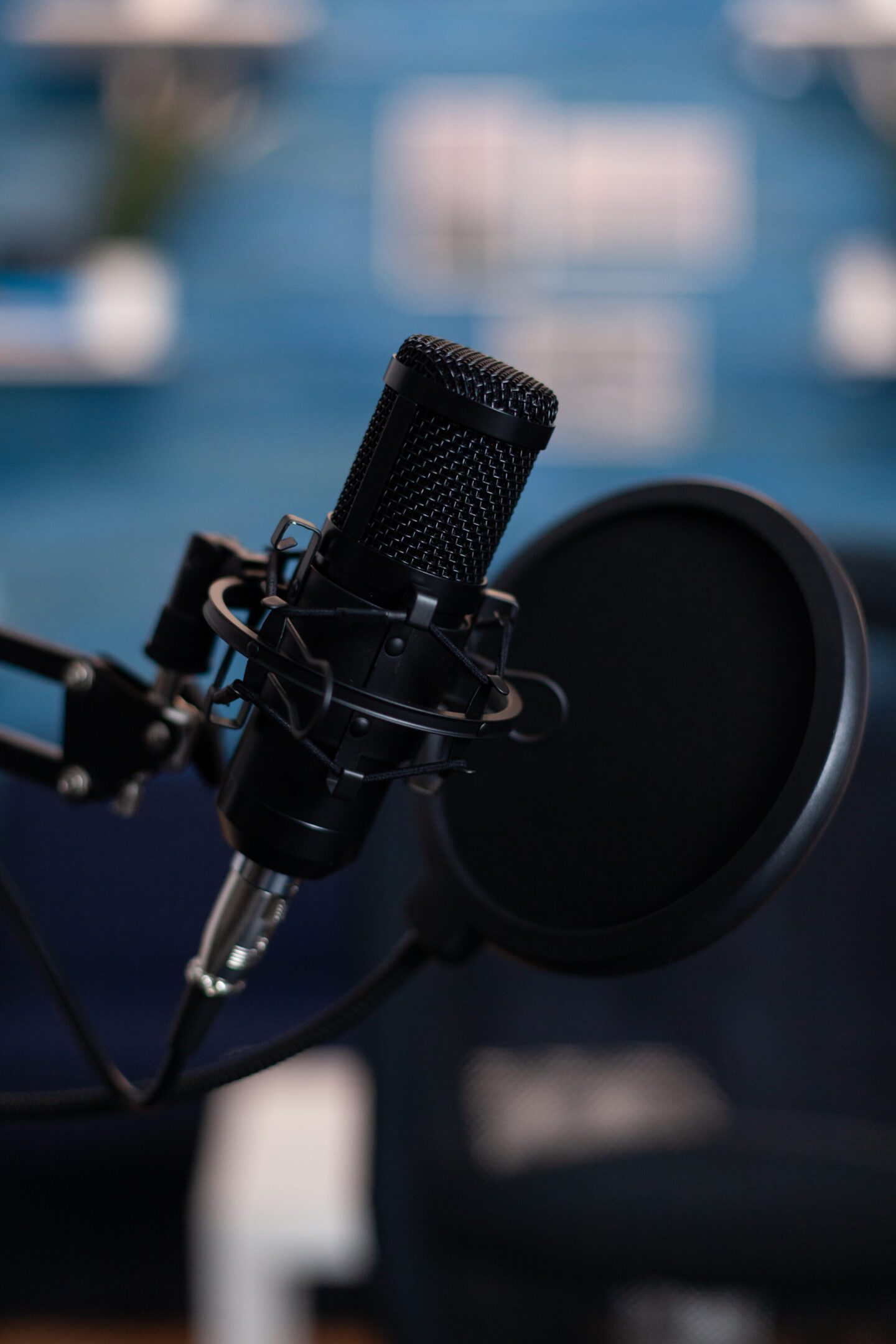 Closeup of professional podcast microphone standing on desk table in podcasting studio equipped with recording equipment. Digital web internet streaming station. On-air show